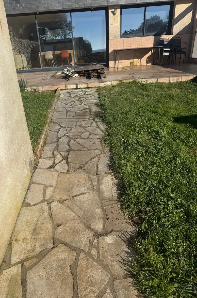 Allée en dallage de pierre posé en opus incertum, bordée de pelouse, jusqu'à une terrasse.