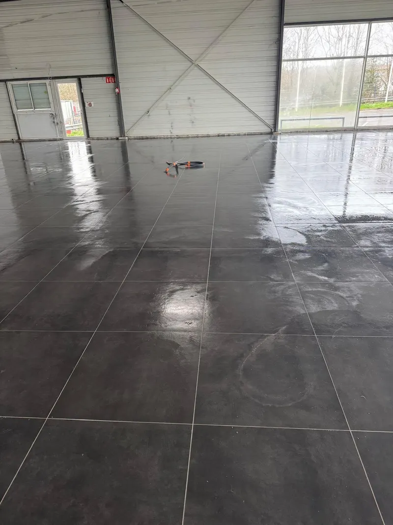 Carrelage gris grand format posé dans un bâtiment d'activité, sol encore humide après nettoyage.