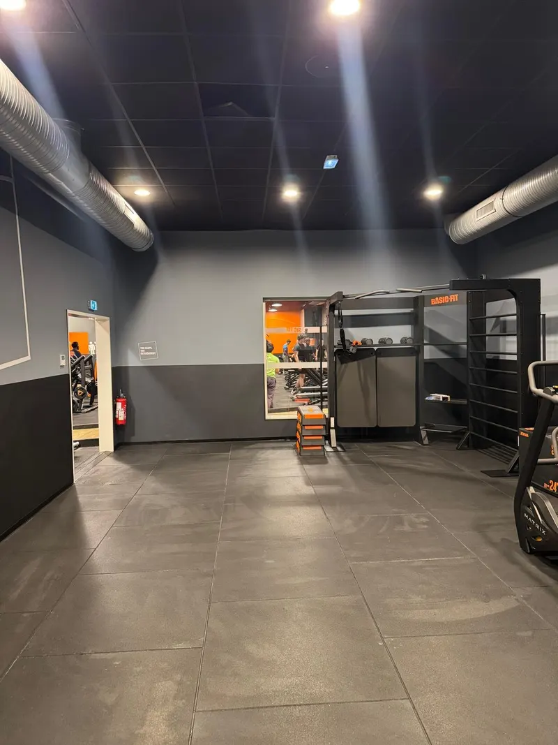 Salle de sport : carrelage gris grand format au sol, murs gris et noir, éclairage encastré.